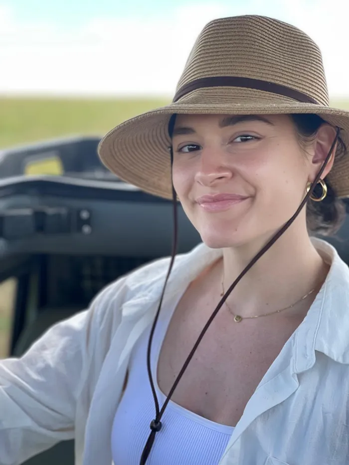 PCOM student physician Angela Ellis, DO '25, smiles wearing a straw hat and leisurely garb outdoors