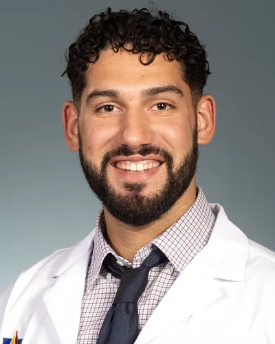 Professional headshot photo of PCOM PA Studies graduate Jesse Rivera wearing is white coat