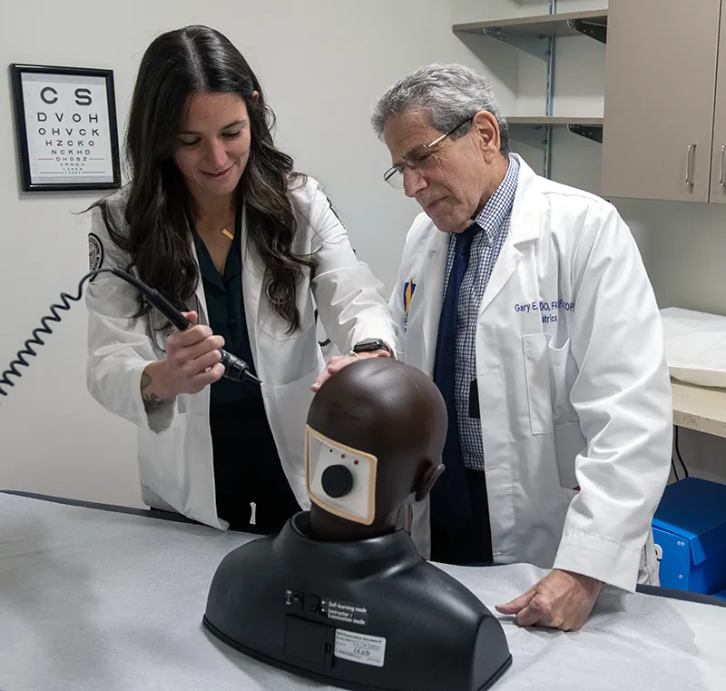 PCOM Georgia student physician Madison Cohen, DO '25, smiles as she learns an exam procedure on a simulation mannequin with a faculty member