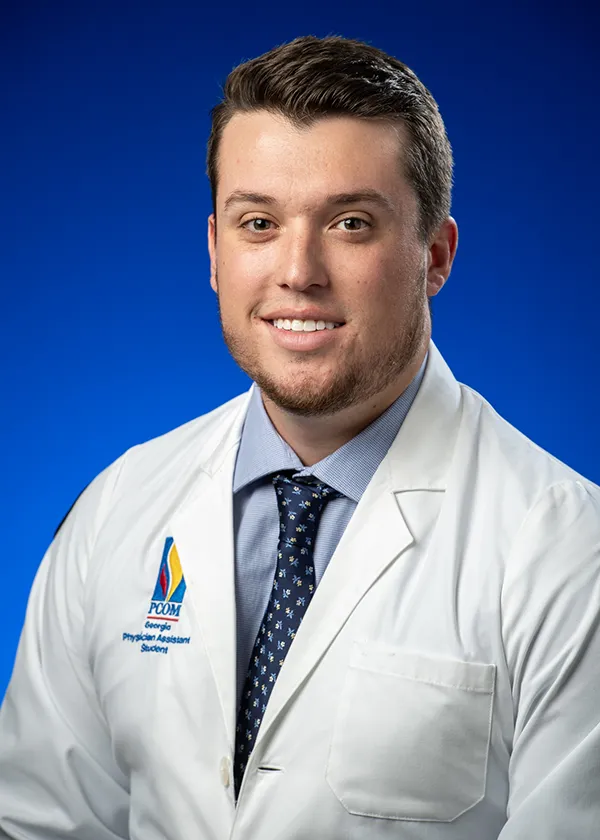 Professional headshot photo of PCOM Georgia physician assistant graduate Turner Brittain, MS/PA '25, smiling and wearing his white coat