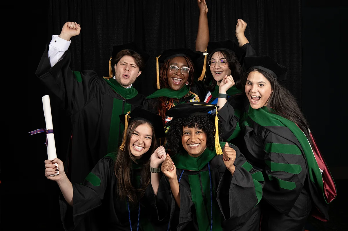 PCOM graduates dressed in regalia celebrate in a fun group photo during the PCOM commencement ceremony