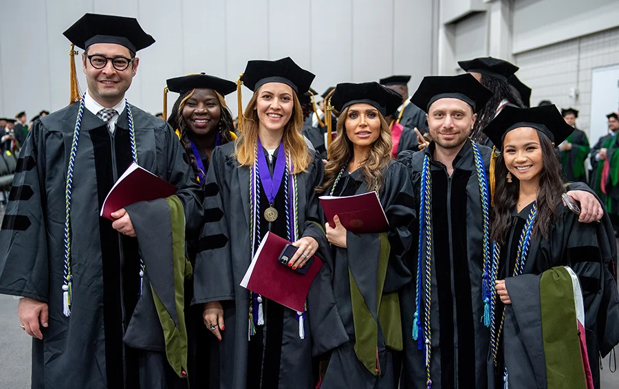 A group of PCOM Georgia medical students smiling in their caps and gowns during a commencement ceremony.