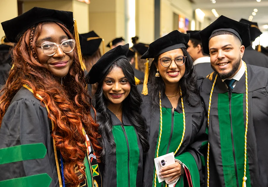 A group of PCOM DO students smiling during a commencement ceremony.