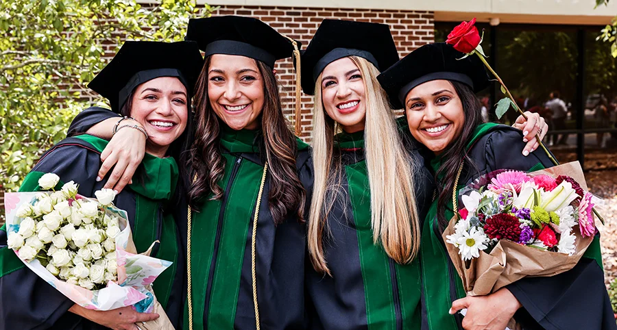 PCOM South Georgia students smiling in a group in their caps and gowns after a commencement ceremony.