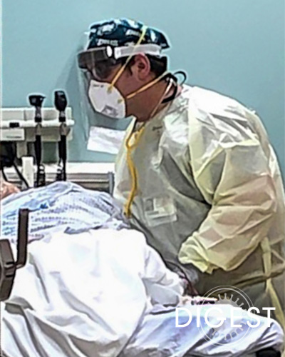 Joshua Baron, DO '03, wearing numerous protective gear as he assists a patient bedside
