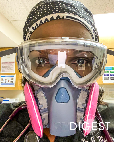 Gina Blocker, DO ’03, looks at the camera through many layers of protective equipment including a heavy duty face mask