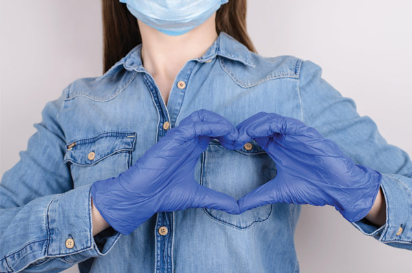 Medical student wearing rubber gloves and a mask making a heart with their hands