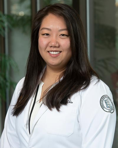 Professional headshot photograph ofHannah Shin, DO ‘19, weaing her student physician white coat