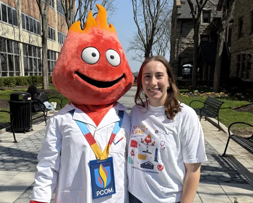 Finny the mascot and a PCOM student
