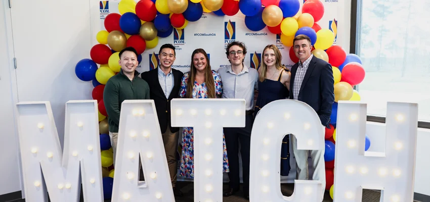 PCOM DO students stand under balloon arch and behind giant "MATCH" letters