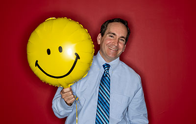 Scott Glassman, PsyD '13, poses with a smiley face balloon.