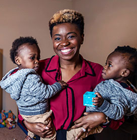 Courtney Hudson Hinton, DO’ 14/MBA holding her twin baby boys