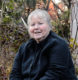 Bernadette Meade, DO '79 smiles while sitting in the woods on an autumn day.