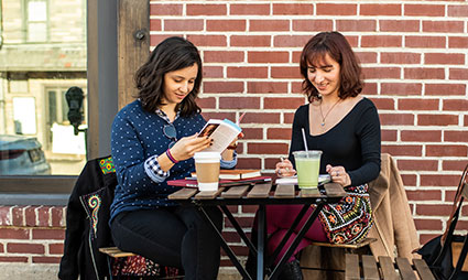 Medical students Kathleen Ackert (DO '20) and Brooke Saffren (DO ’20) read and color at an outdoor cafe table in Philadelphia.