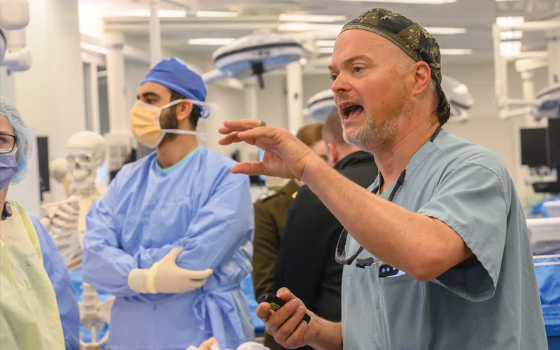 John Chovanes, DO ’02, RES ’06, speaking to an operating room full of surgeons