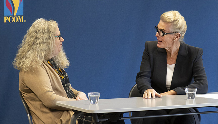 Dr. Ann Koch speaks with a guest at a table during a transgender medicine talk at PCOM