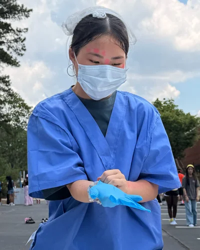 High school student tries on face mask and nitrile gloves