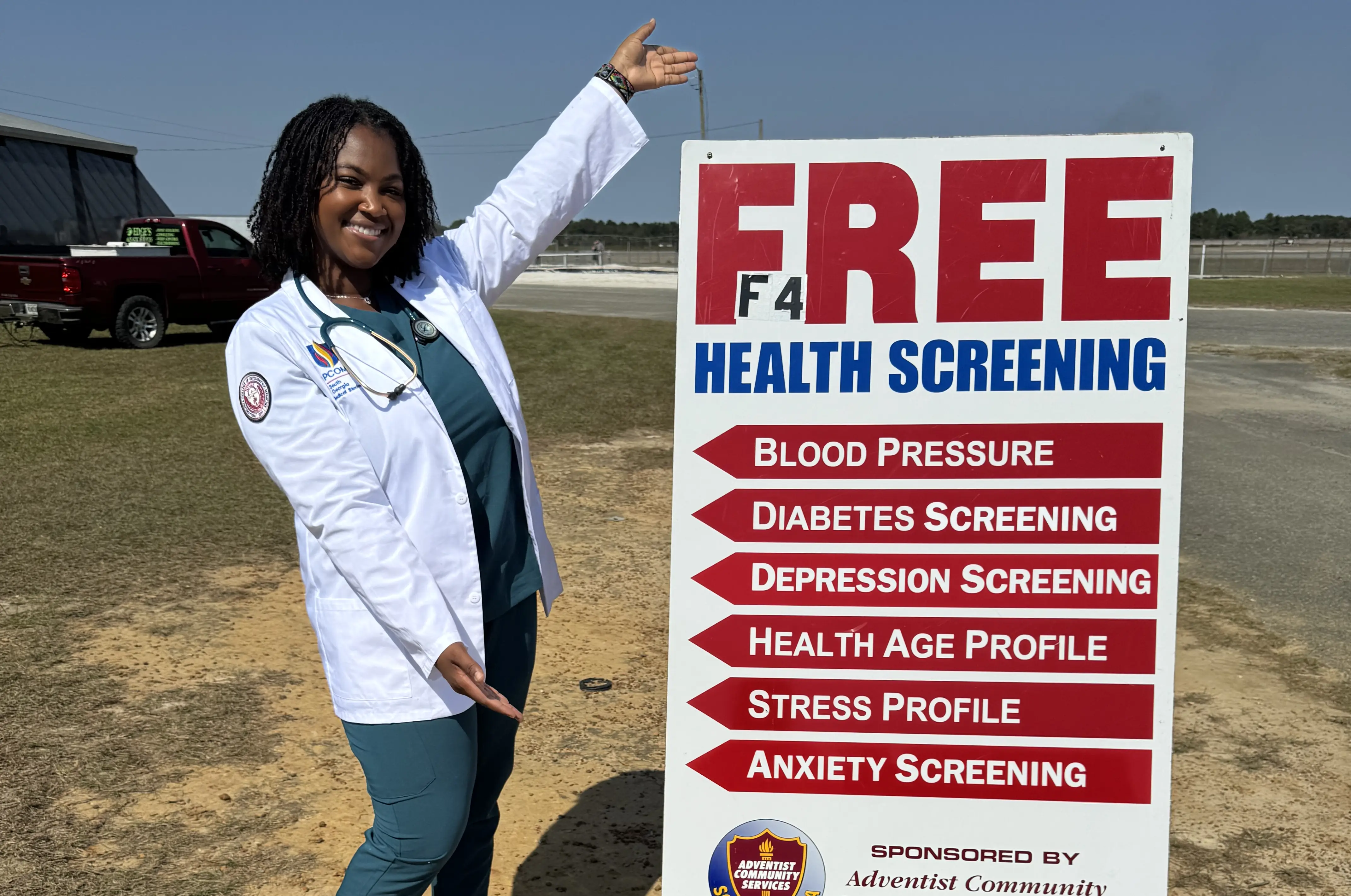 Sydney Williams posing with a free health screening sign.
