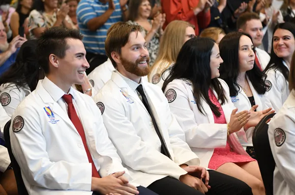PCOM Georgia physical therapy students smile and clap during the DPT White Coat Ceremony