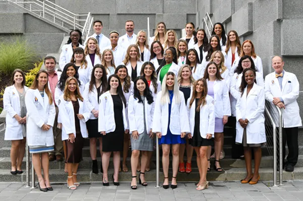 Group photo of PCOM Georgia physician assistant studies and faculty smiling outside after the white coat ceremony