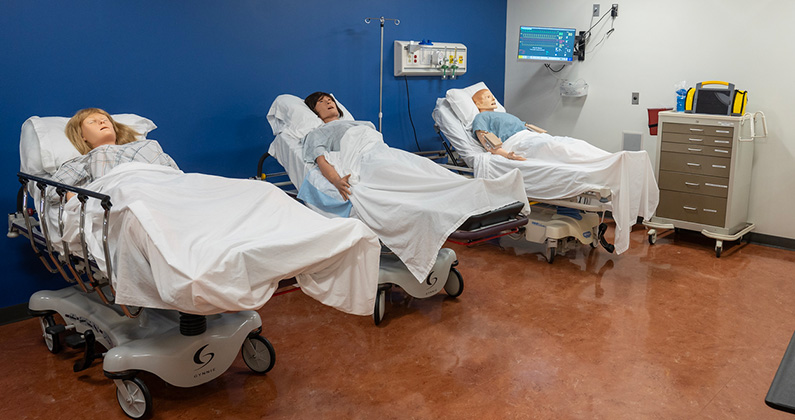Three standardized patient mannequins in medical bays at the PCOM Georgia Simulation Center