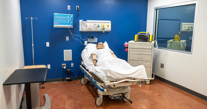 Advanced patient mannequins in a hospital bed within a simulation room at PCOM Georgia