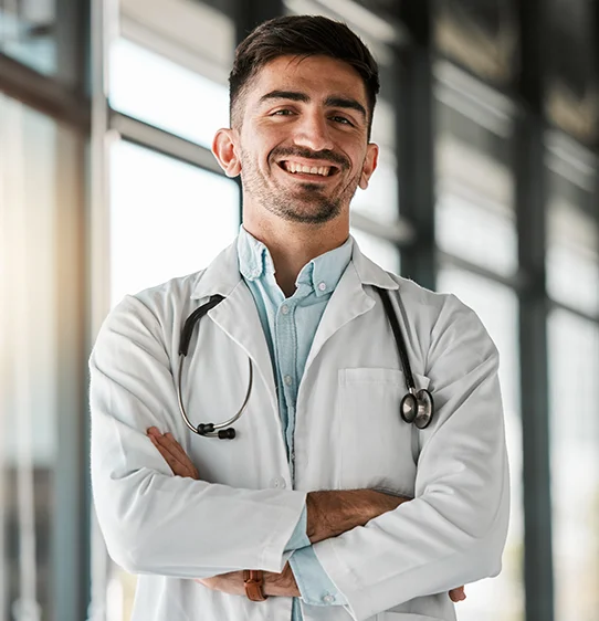 Young physician smiling while wearing a stethoscope and doctor white coat during a visting rotation at PCOM