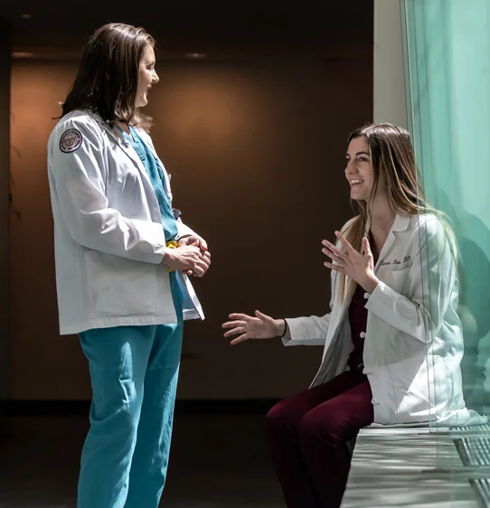 Young physicians smiling and talking in a lobby area during a fellowship program at PCOM