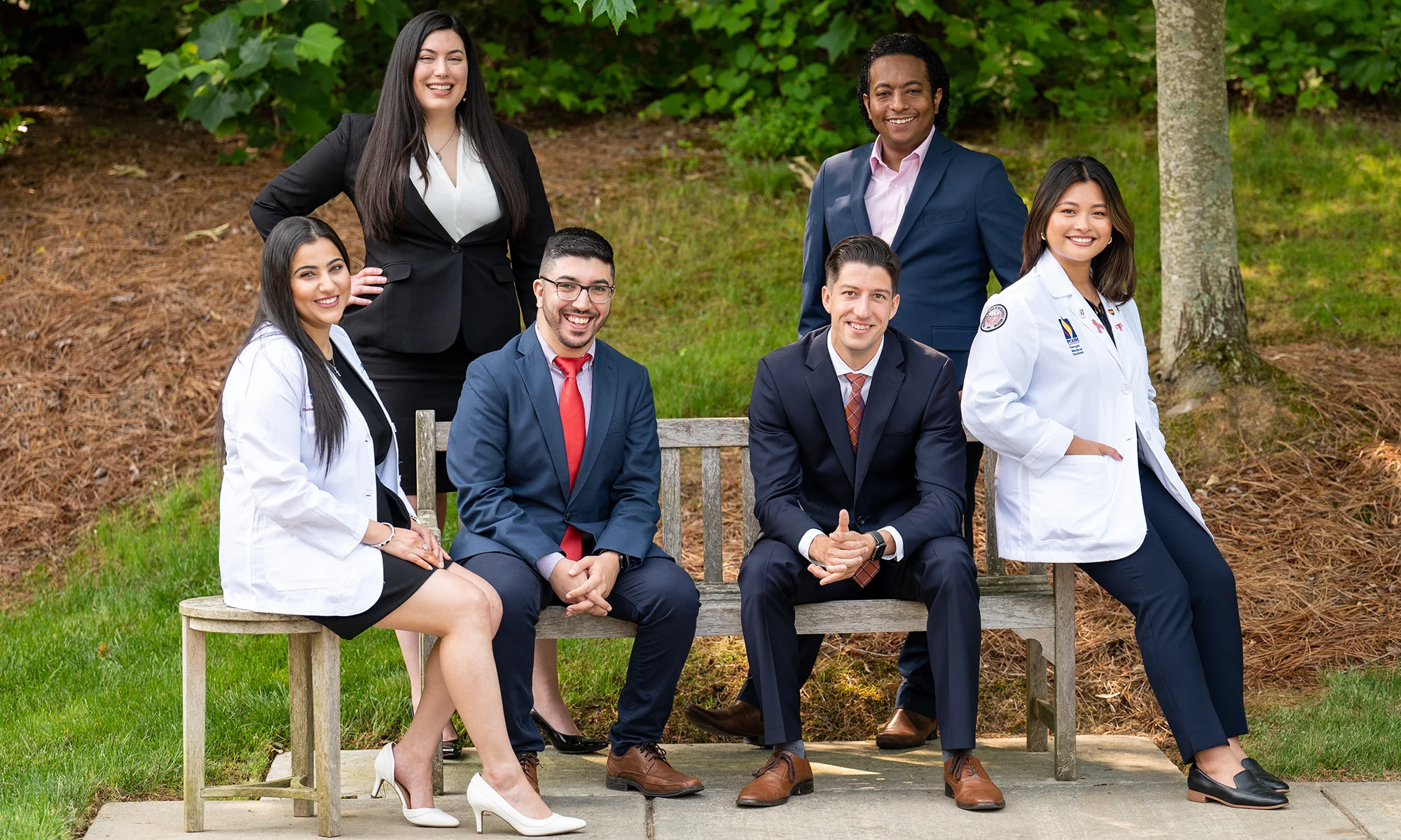 PCOM Georgia medical and graduate students smiling on a bench while dressed in professional attire