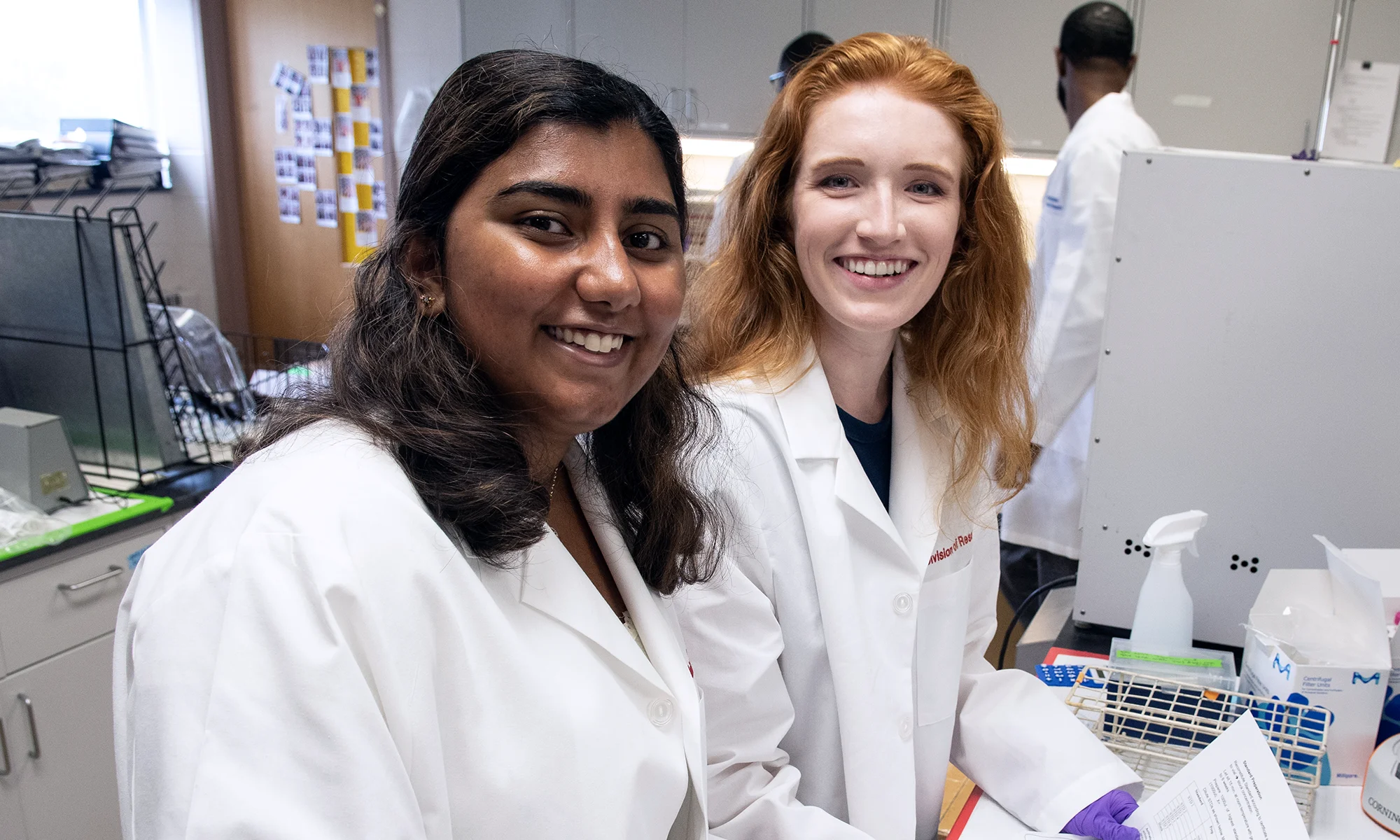 Two PCOM Georgia students pursuing the Advanced Biomedical Sciences concentration smile in a laboratory