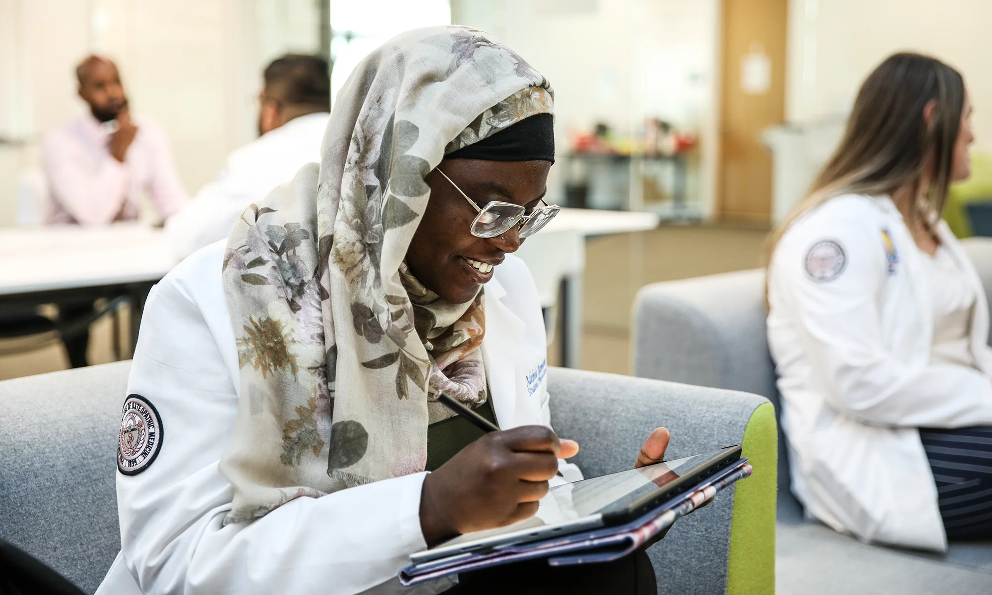 A PCOM South Georgia med student smiles while looking at cancer biology research on a tablet in the information commons