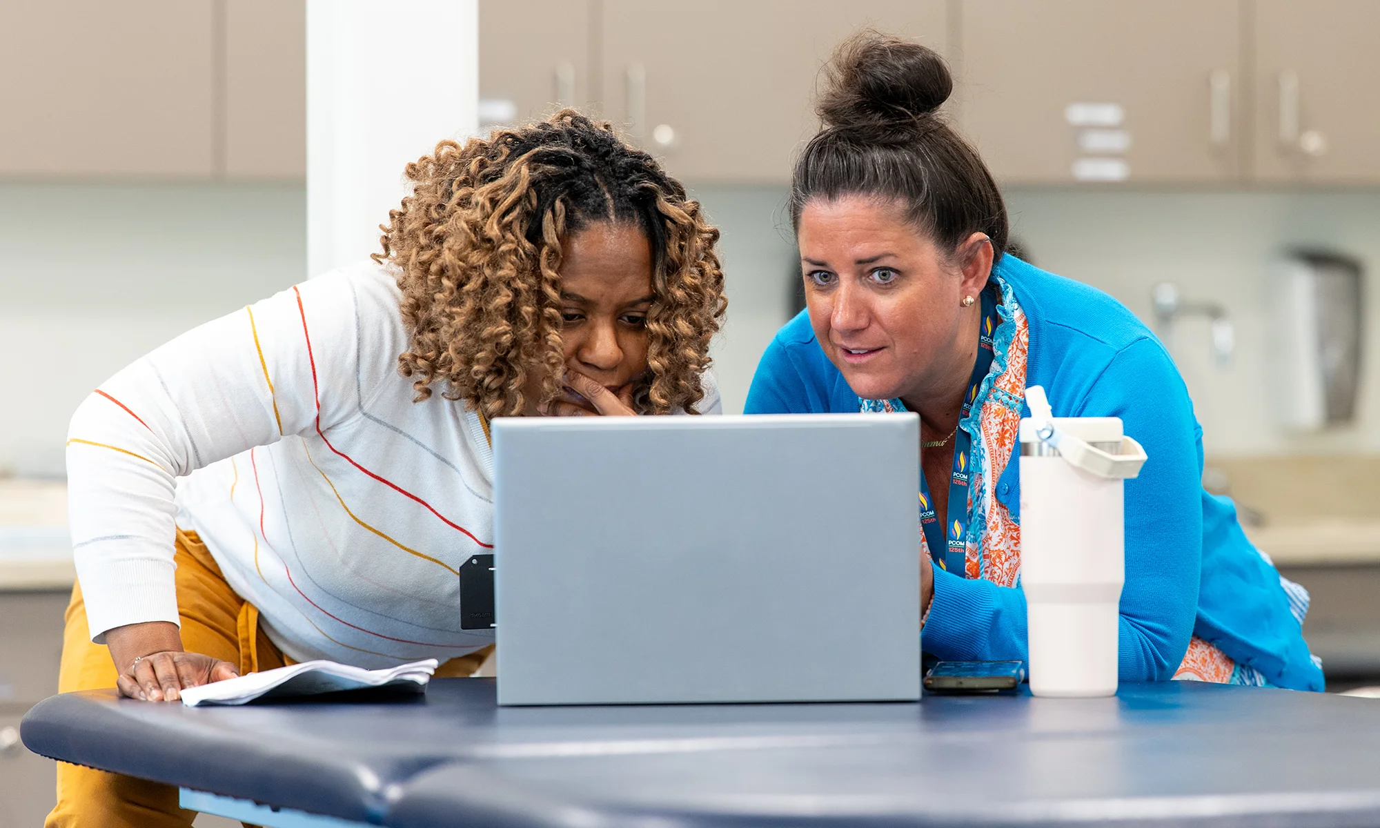 PCOM faculty from different departments working on a laptop in a classroom during an interprofessional education exercise