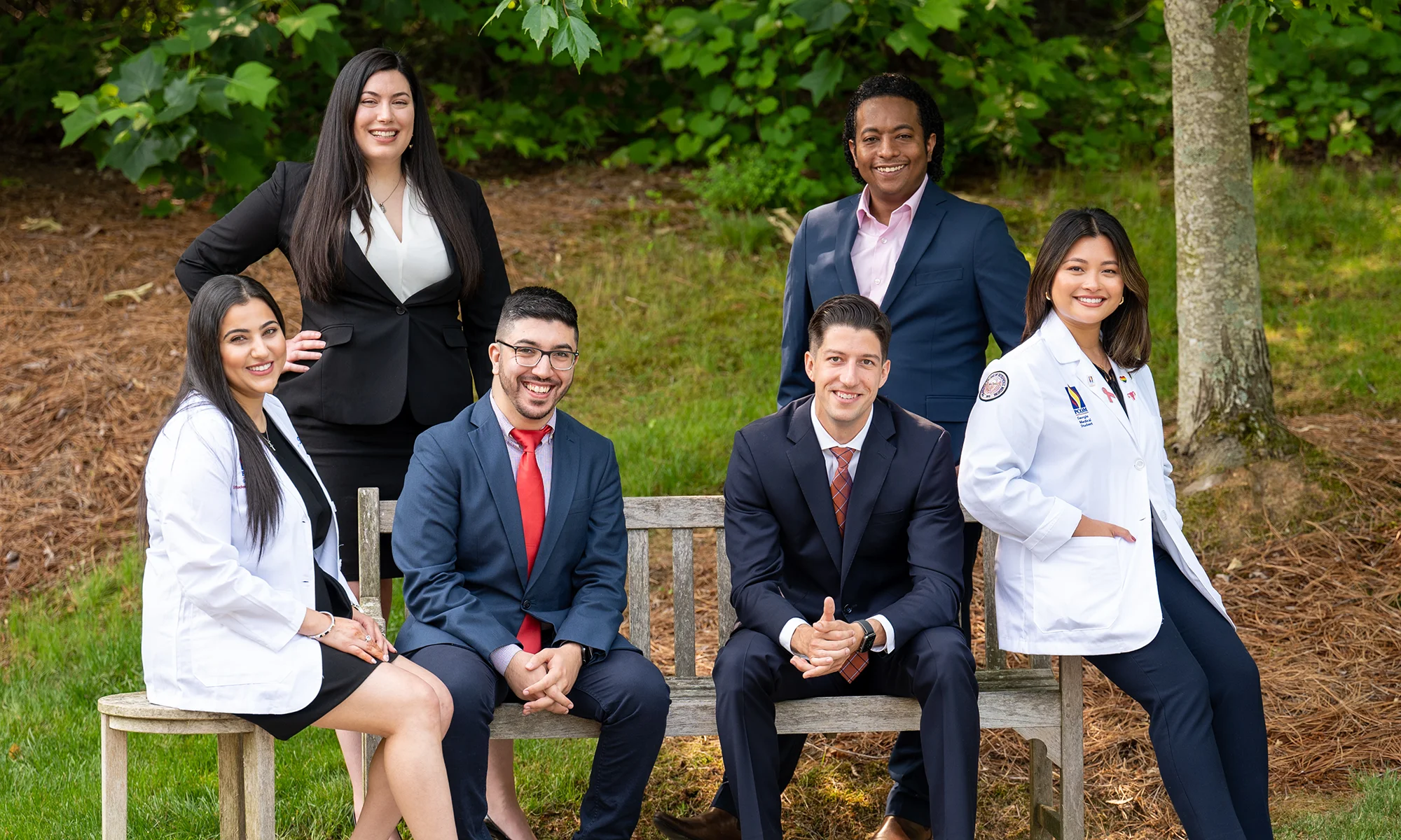 A group of PCOM Georgia graduate and medical student smiling on a bench representing multidisplinary degree options