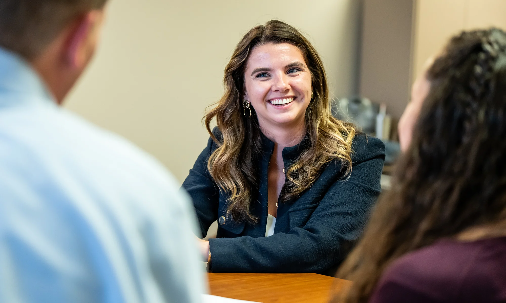 PCOM student smiling while working with a parent and middle school student during a clinical learning assignment