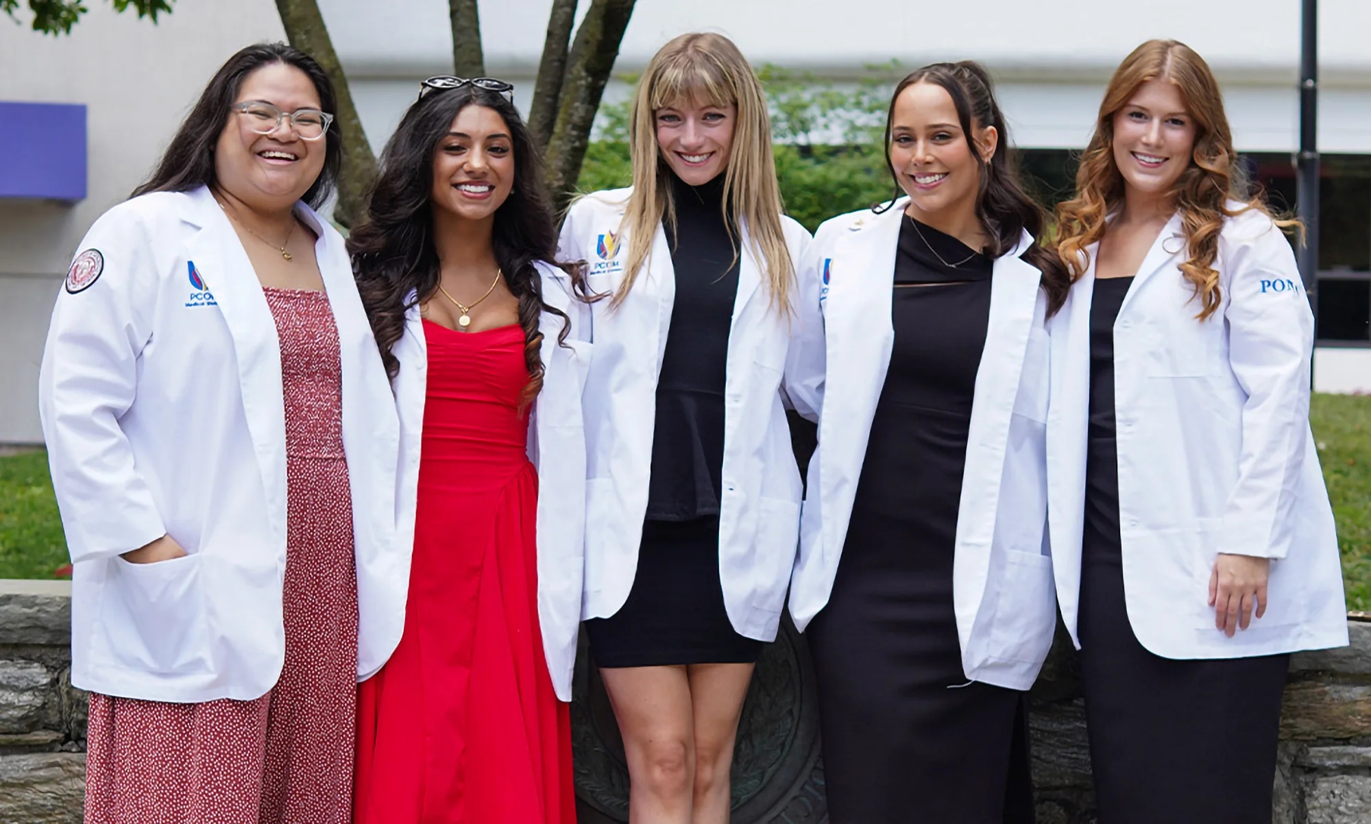 A group of PCOM medical students smiling in their new white coats after the white coat ceremony