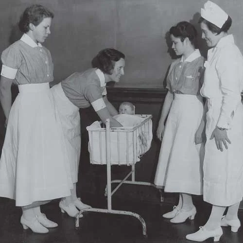 Black and white photo of nurses smiling during instruction.