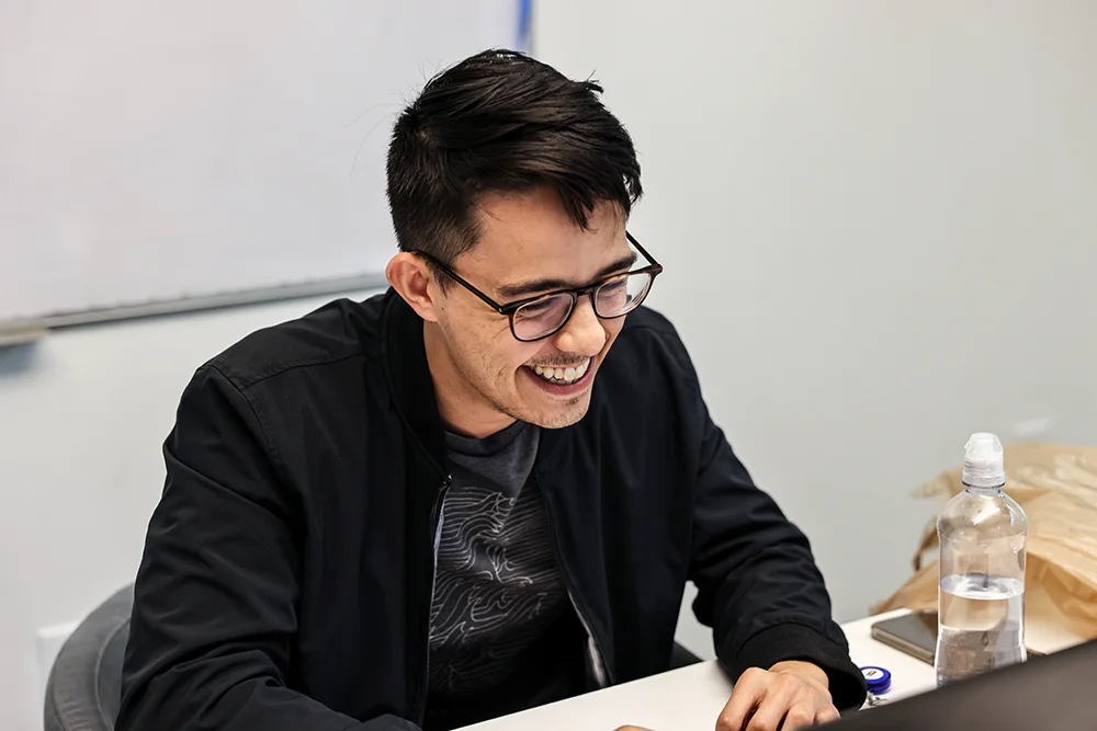 A PCOM medical laboratory science student smiles while working on online coursework on a laptop