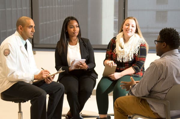 Photo of a group of PCOM students having a discussion. PCOM's values include embracing diversity, advancing equioty and inclusion.