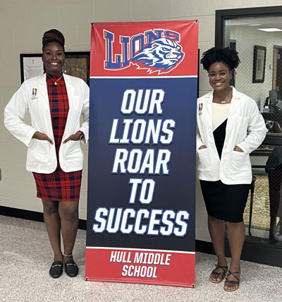 PCOM Georgia students pose next to Hull Middle School banner