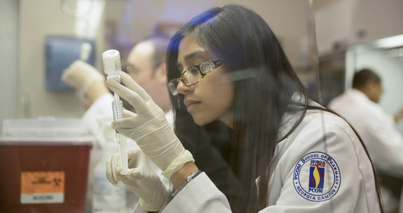 PharmD student measures medication with syringe in lab classroom