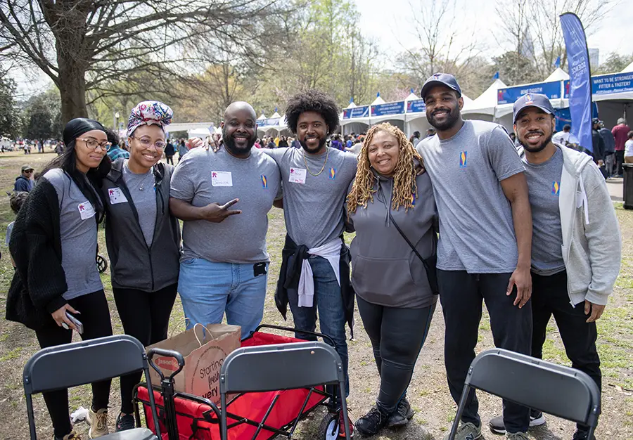 PCOM Georgia students and staff smile in front of a row of sponsor tents at the Atlanta Science Festival