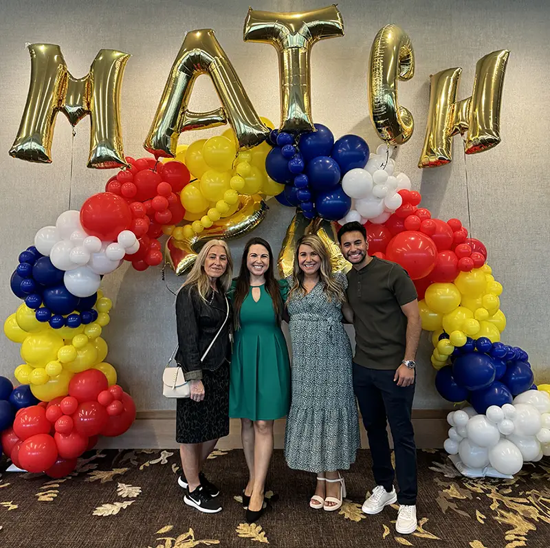 Janine Kfouri and family members smile under a display of balloons during a PCOM Georgia Match Day event