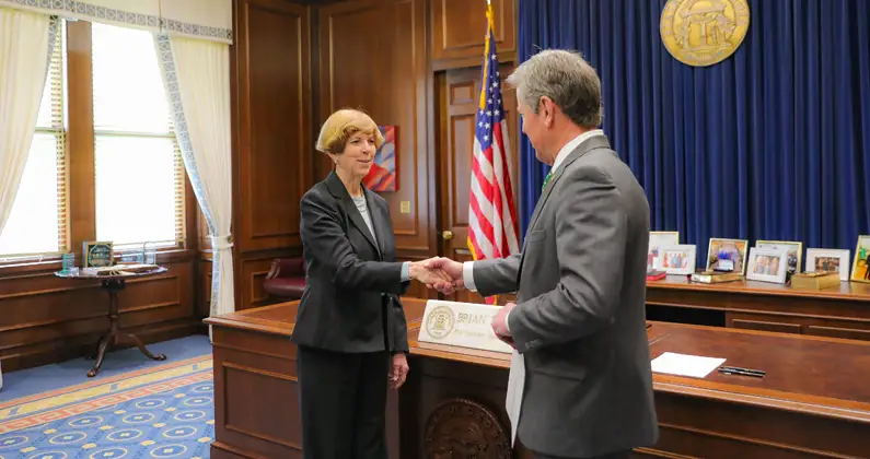 Linda R. Adkison, MS, PhD, shakes hands with Governor Brian Kemp at the Georgia Capitol building.