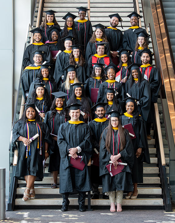 PCOM Georgia's PA Studies Class of 2022 smiles in regalia on a flight of steps