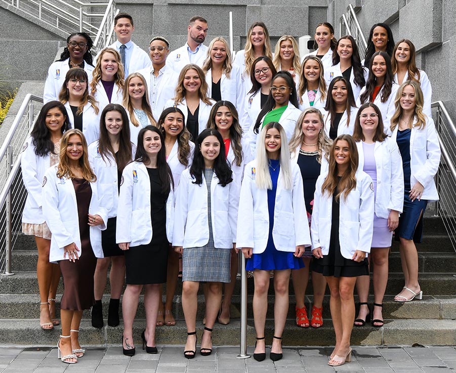 Physician assistant studies students take a group shout and smile donning their new white coats during the white coat ceremony