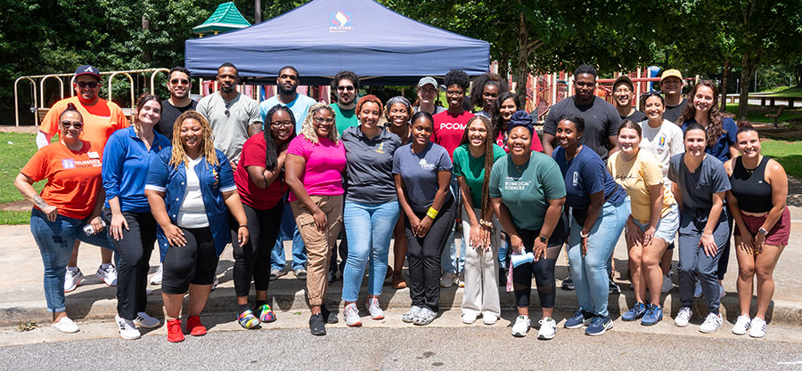 PCOM students smile in front of a playground in Lawrenceville before the student-organized back-to-school community event kicks off