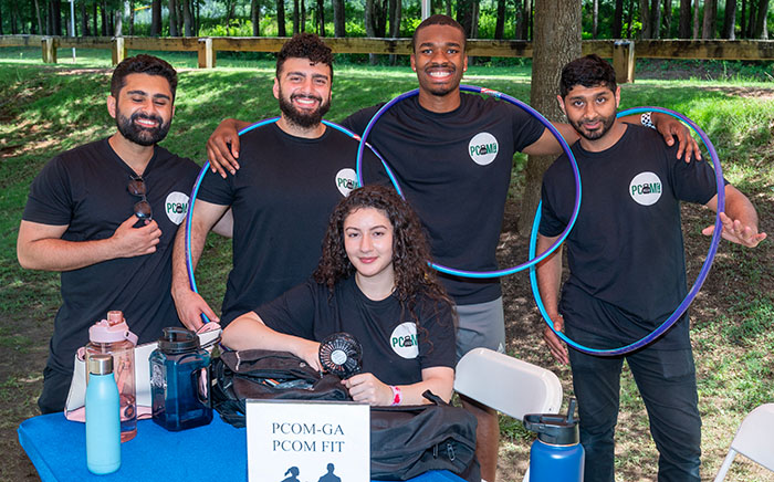 PCOM Georgia students smile at an information table at the community event