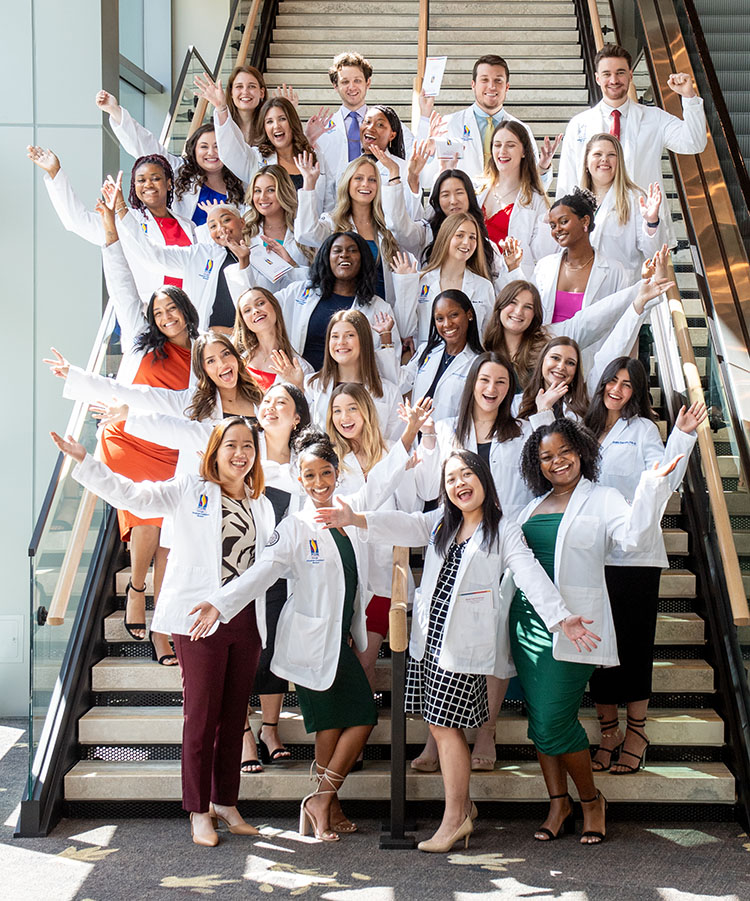 The PCOM Georgia PA Studies Class of 2025 poses on a stairwell following their white coat ceremony