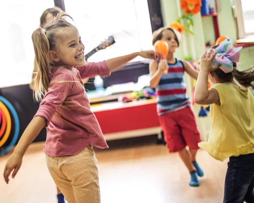 Young children dance and play with musical instruments during elementary school