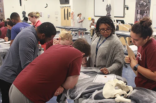 Physical Therapy students gathered around an exam table for an escape room study game
